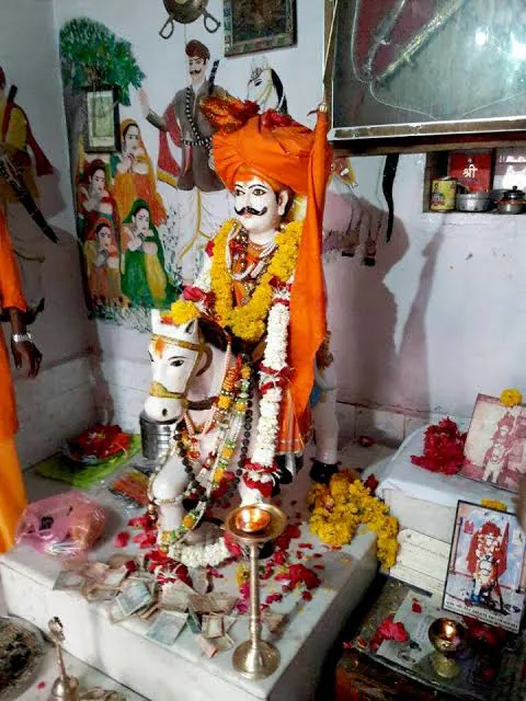 Idol of Jam Abda on horseback, garlanded with marigolds, inside his shrine