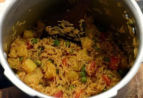 Spiced rice with potato, peas and tomato in a cooker