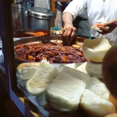 Dabeli masala cooking in a large pan at a street stall