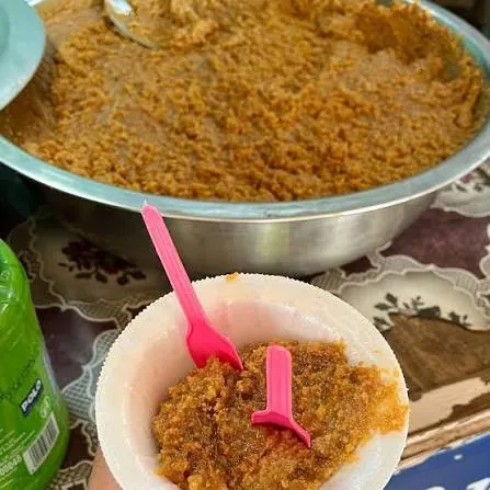 Bowl of brown, grainy meetha mava with a spoon