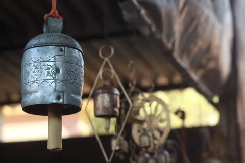 Hand-hammered metal bell with punched floral designs hanging in a Nirona workshop