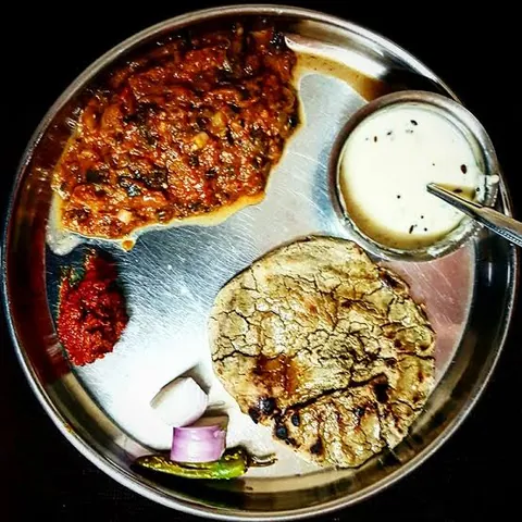 Thali of bajra no rotlo with odho, garlic chutney, onion, chilli and a bowl of chaas