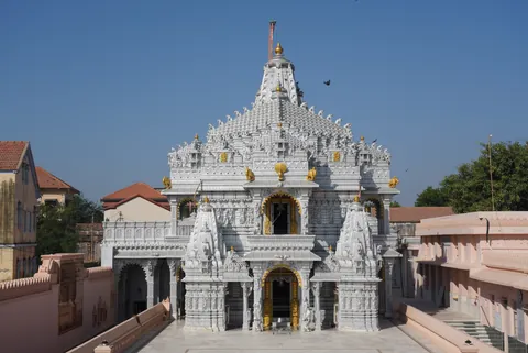 White marble Jain temple with carved spires and gilded details at Suthari